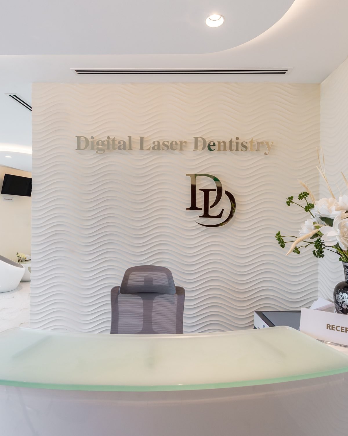 The Digital Laser Dentistry reception desk with the DL monogram on the textured feature wall